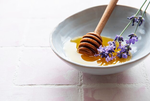 Bowlwith miel y flores frescas de lavanda sobre un fondo de mosaico rosa