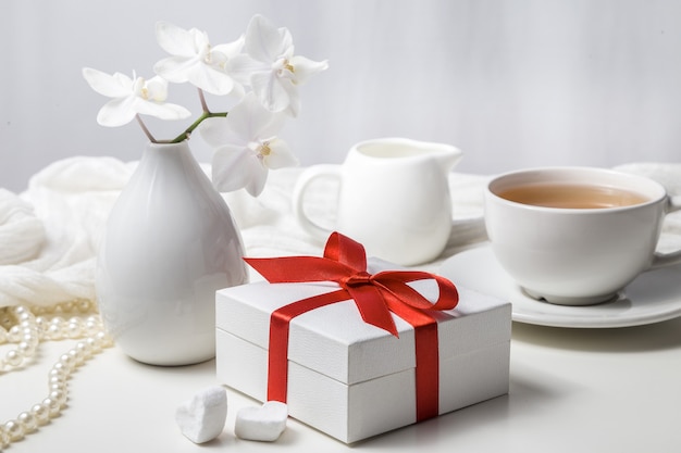 Box mit einem Geschenk und einer weißen Orchidee auf einem weißen Hintergrund.