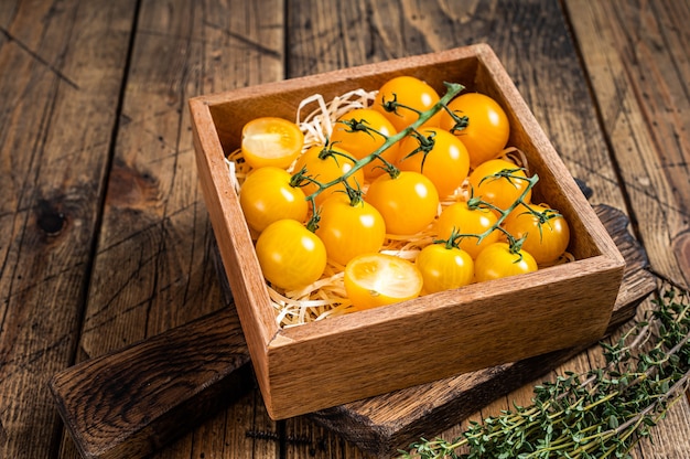 Box mit gelber Kirschtomate. Holztisch . Draufsicht.