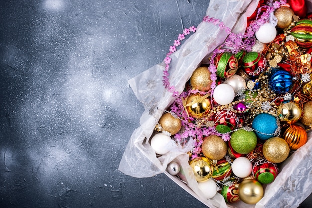 Box mit Spielzeug unterschiedlicher Farbe für einen Weihnachtsbaum auf einem schwarzen Hintergrund