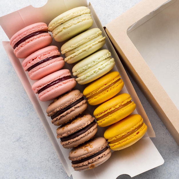 Box mit verschiedenen leckeren Macarons auf weißem Hintergrund