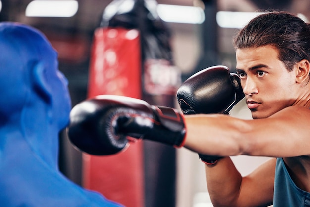 Boxe de aptidão e homem na academia para treinamento de exercícios e treino com um manequim para velocidade rápida e soco ágil para jogo esportivo ou competição Concentre-se no rosto e luvas de boxe no atleta boxer para lutar