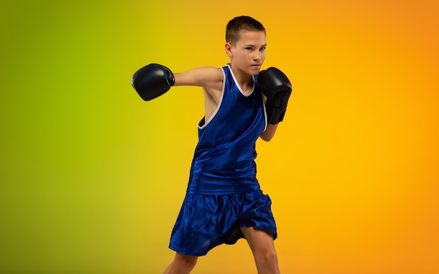 Boxeador adolescente contra el estudio de neón degradado en movimiento de patadas, boxeo