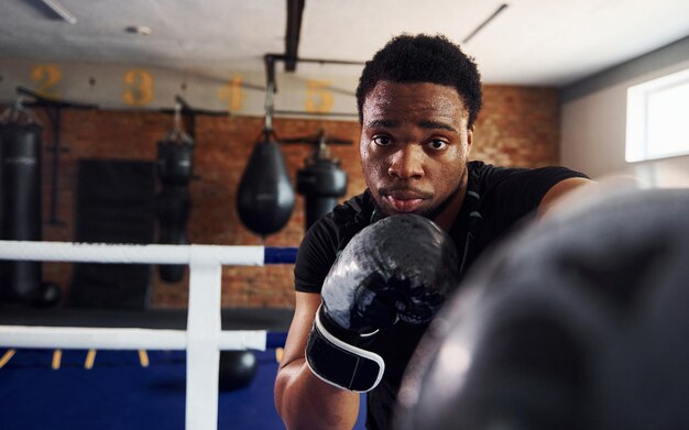 Boxeador afroamericano fuerte en ropa deportiva tiene práctica en el gimnasio