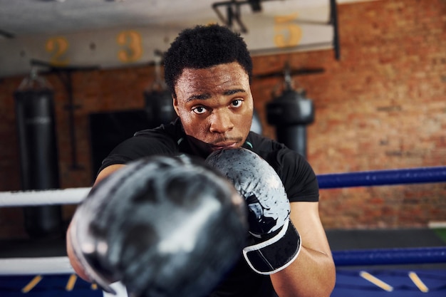 Boxeador afroamericano fuerte en ropa deportiva tiene práctica en el gimnasio