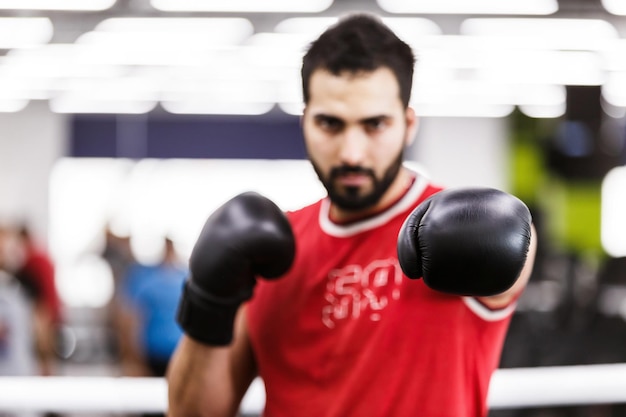 Boxeador barbudo viste camisa roja y guantes negros en el ring