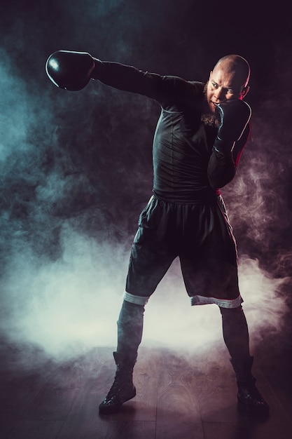 Foto boxeador esportista lutando em um espaço negro com fumaça