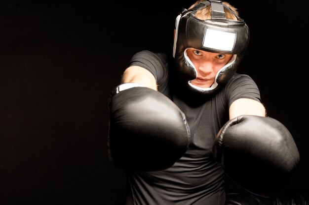 Boxeador golpeando hacia la cámara con sus dos puños enguantados con una mirada de determinación.