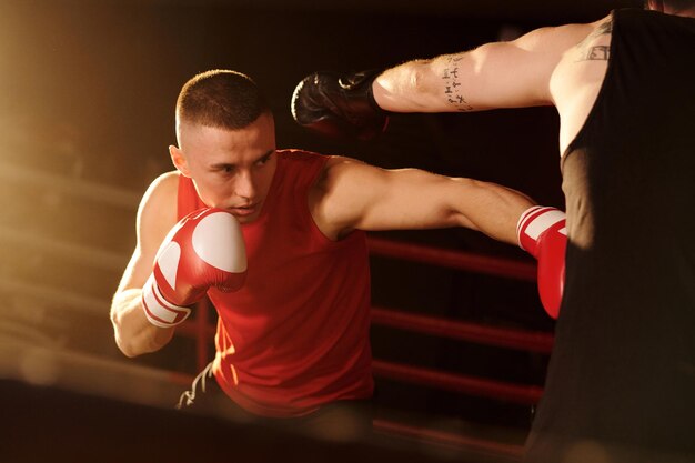 Foto boxeador mais jovem em roupas desportivas a bater no rival