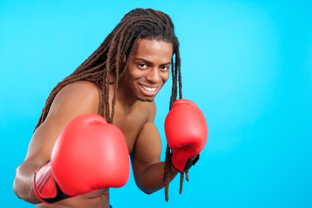 Boxeador masculino latino profesional con rastas con guantes de boxeo rojos