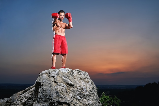 Boxeador masculino muscular mirando a la cámara al aire libre