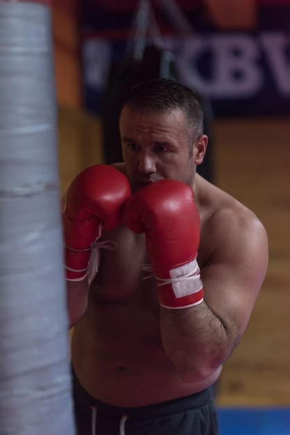 boxeador muscular profesional entrenando en un saco de boxeo mientras se prepara para la próxima pelea