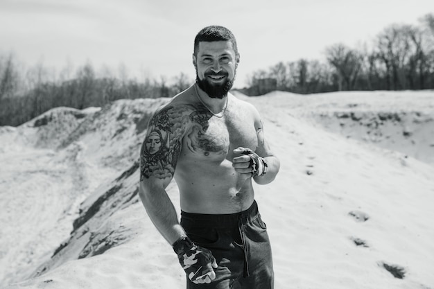 Boxeador musculoso malhando na areia com o torso nu