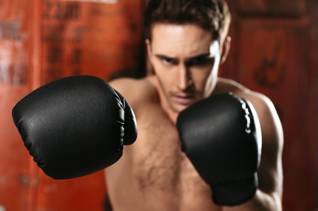 Boxeador de pie en un gimnasio y posando con las manos. Centrarse en las manos.