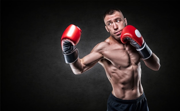 Boxeador profesional en guantes rojos practicando golpes. Concepto de boxeo. Técnica mixta