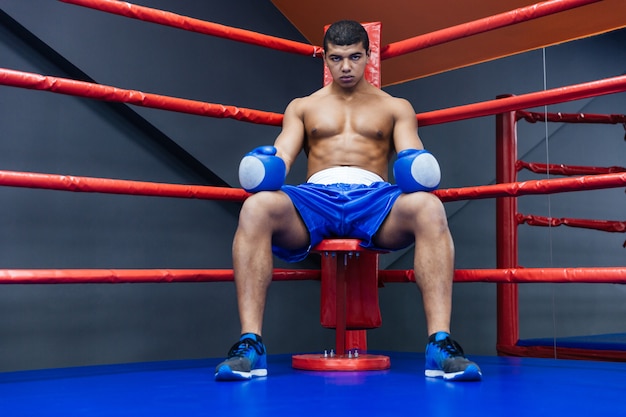 Boxeador profissional masculino sentado no canto do ringue de boxe