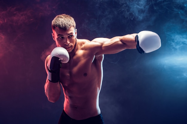 Boxeador sem camisa com luvas em fundo escuro. isolar