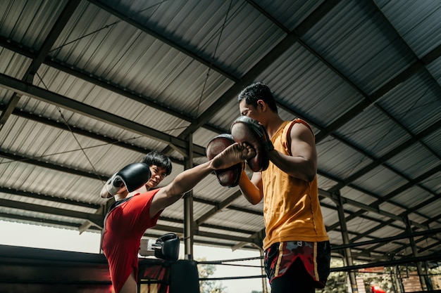 Boxeador y su entrenador haciendo sparring en el ring. Boxer y su entrenador practicando algunos movimientos.