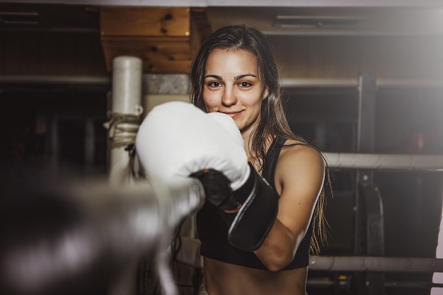 La boxeadora feliz y sonriente está lista para pelear mientras está de pie en su esquina en el ring.