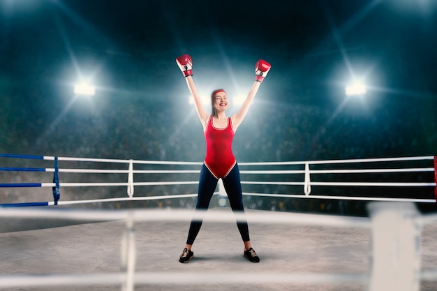 Boxeadora en ropa deportiva roja con las manos en el anillo