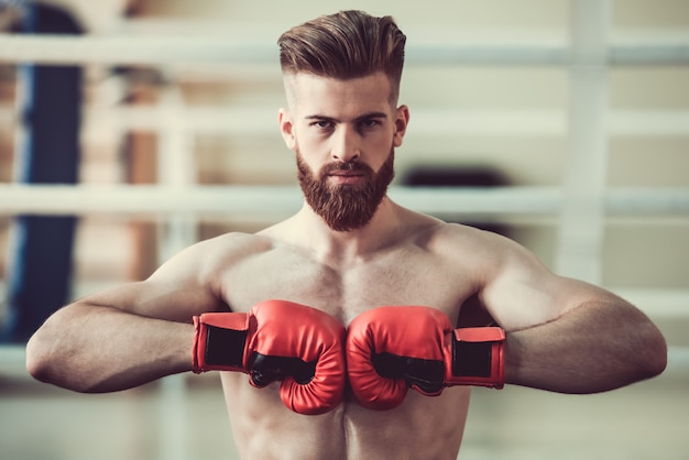 Boxer barbudo con torso desnudo en guantes de boxeo rojos.