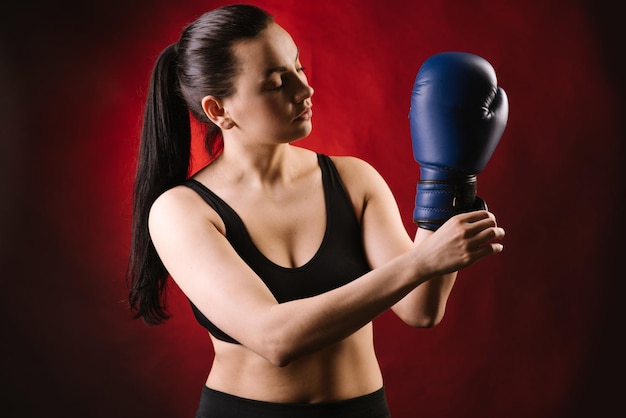 Foto boxer de esporte radical usando luvas de boxe azuis em fundo vermelho escuro