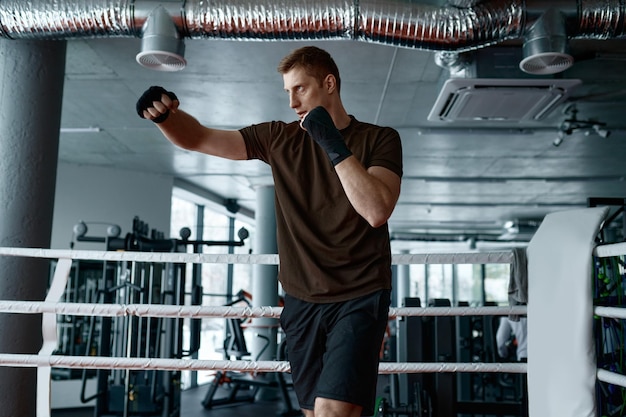 Boxer de homem de confiança faz exercício de boxe de treinamento esportivo perfurando ar no anel vista lateral em câmera lenta