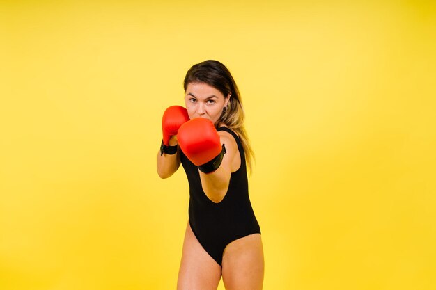 Boxer de mulher em luvas treinando em fundo amarelo vermelho preto