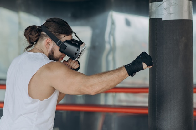 Boxer des jungen Mannes im Kopfhörer-Training VR 360 für das Treten im Kampf der virtuellen Realität