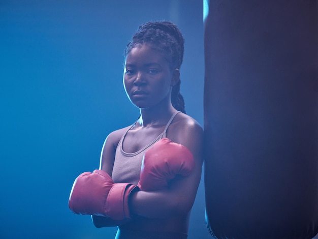 Boxer fitness e ginásio de uma mulher negra em esportes profissionais para força e motivação Retrato de uma mulher africana em boxe sério e confiante no health club em pé pelo saco de pancadas
