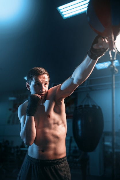 Boxer im Verbandtraining mit Tasche im Fitnessstudio