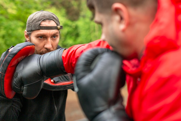 Boxer-Manntraining mittleren Alters mit Trainer im Freien