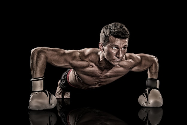 Boxer mit nackter Brust. Athletische Bodybuilderpose in Hosen. Gladiator oder Atlant in Boxhandschuhen. Sport und Training. Mann mit muskulösem Körper.