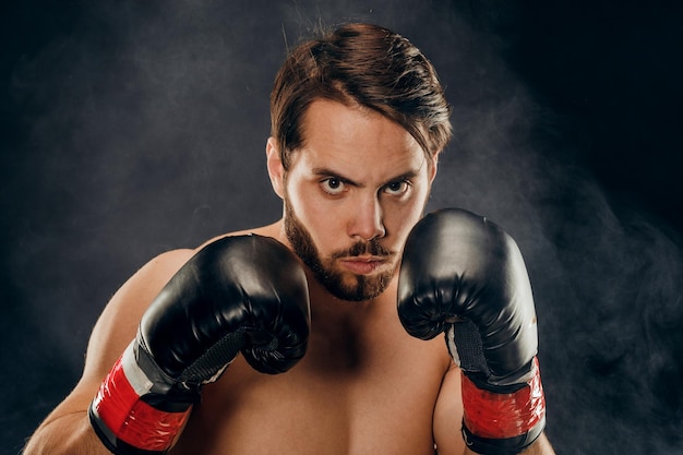 Boxer sem camisa com luvas em fundo escuro em fumaça