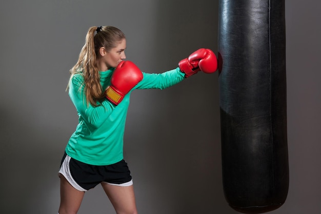 Boxfrau in grüner Sportkleidung und roten Boxhandschuhen