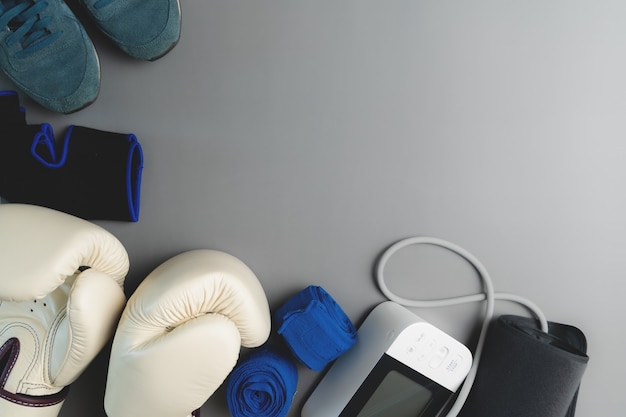 Boxhandschuh, Blutdruckmessgerät, Fitnessgeräte auf grauem Hintergrund mit Kopierraum