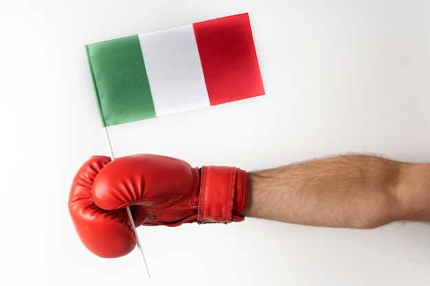 Boxhandschuh mit italienischer Flagge. Boxer hält Flagge von Italien. Weiße Wand.