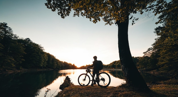 Boy Stop am See bei Sonnenuntergang mit dem Fahrrad Mountainbiken in den Bergen