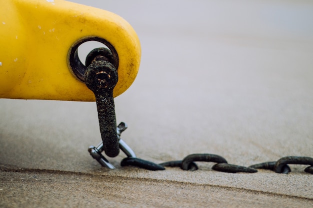 Boya cónica amarilla con una cadena en la arena de la playa húmeda