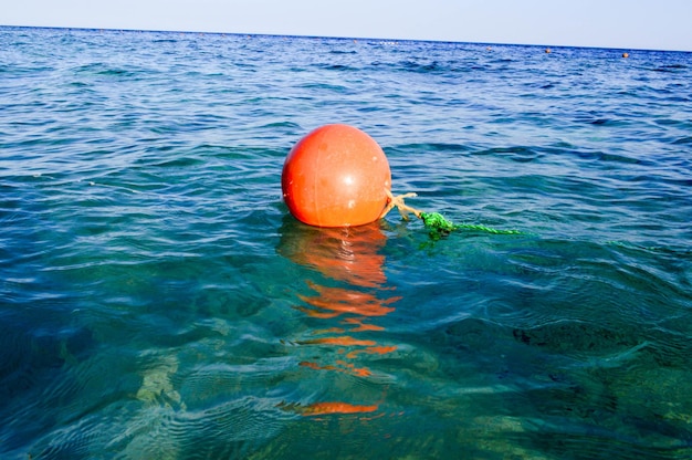 La boya de rescate de plástico redonda grande naranja flota en el mar azul salado por seguridad