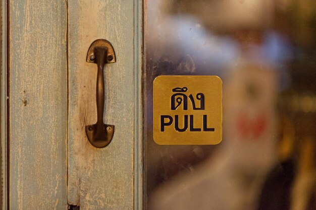 Brace firma la puerta de una tienda diciendo en tailandés e inglés Pull