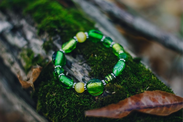 Bracelete joia de vidro artesanal "faça você mesmo" sobre fundo de floresta de madeira natural. Ideia de negócio, ganhar dinheiro para um hobby. Habilidades úteis em quarentena