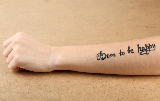 Braço feminino com tatuagem em fundo de madeira
