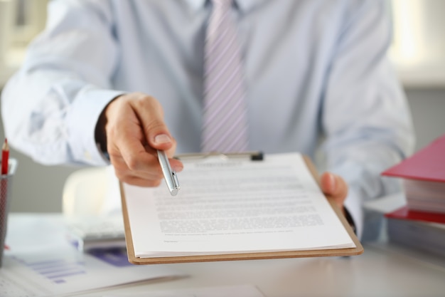 Braço masculino de terno oferece formulário de contrato em