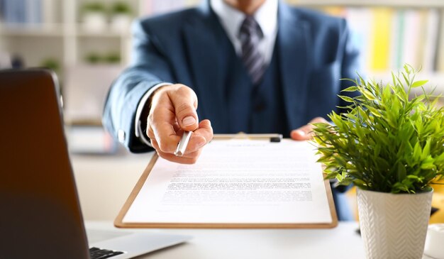 Braço masculino de terno oferece formulário de contrato na área de transferência