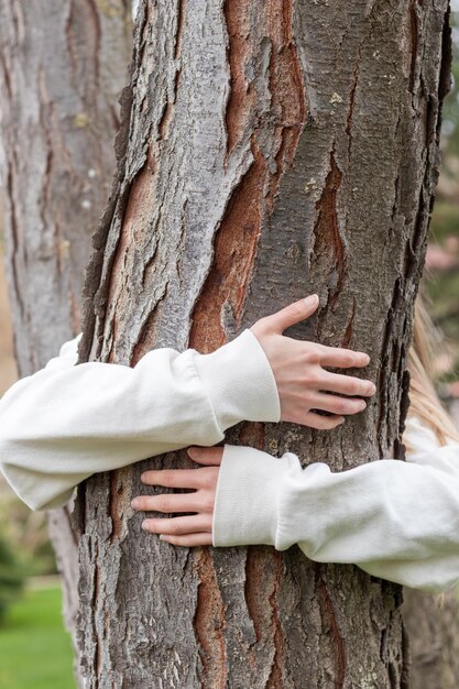 Braços abraçando o tronco de uma árvore como um símbolo para o dia da terra