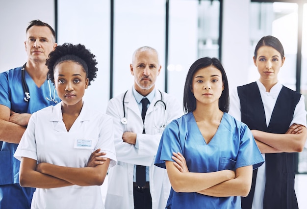 Braços cruzados médicos e retrato de grupo de médicos em pé no corredor com confiança Diversidade séria e equipe de profissionais de saúde em uma clínica médica ou hospital