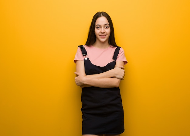 Braços de cruzamento jovem menina bonita natural, sorrindo e relaxado