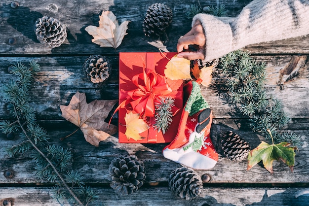 Braços de mulher fazendo decoração de natal em uma mesa de madeira ao ar livre