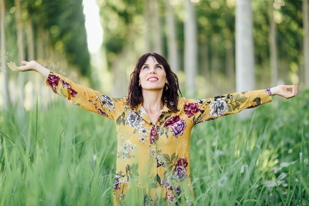 Braços de mulher levantados, apreciando o ar fresco na floresta verde